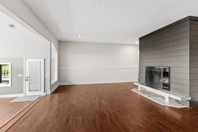 an empty room with wooden floor fireplace and windows