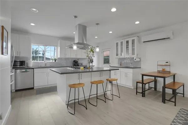 a kitchen with stainless steel appliances kitchen island granite countertop a table chairs sink and cabinets