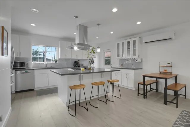 a kitchen with stainless steel appliances kitchen island granite countertop a table chairs sink and cabinets