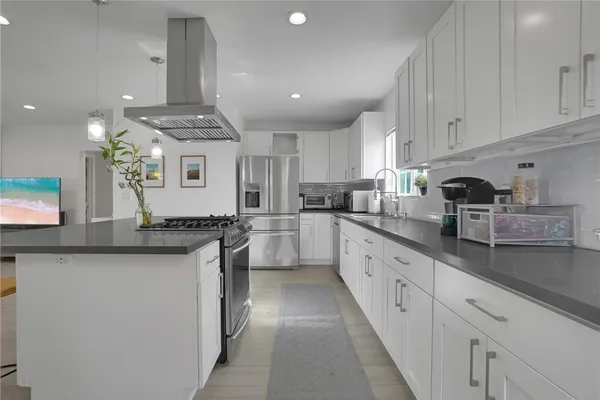 a large kitchen with stainless steel appliances granite countertop a sink and cabinets