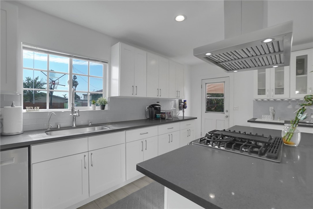 3541 Gibson Road El Monte, CA 91731 - Photo 21 of 38 a kitchen with sink a stove and white cabinets with wooden floor