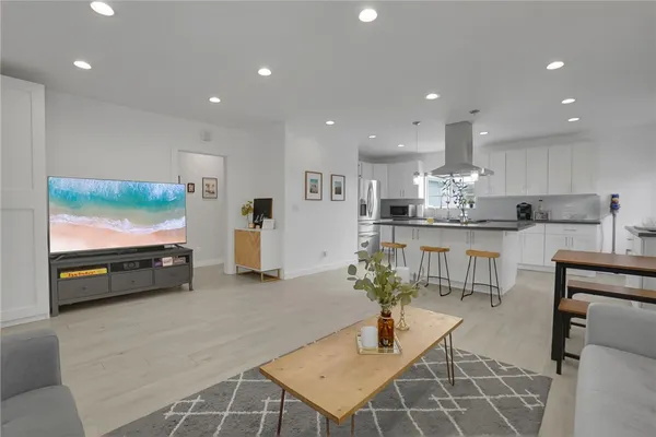 a living room with stainless steel appliances kitchen island furniture and a flat screen tv