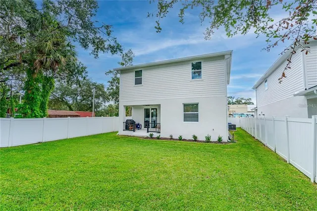 a view of a backyard with table and chairs and a large tree