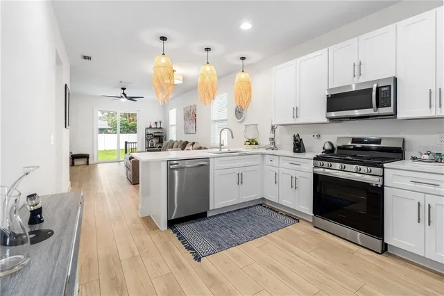 a kitchen with stainless steel appliances a stove a sink and white cabinets