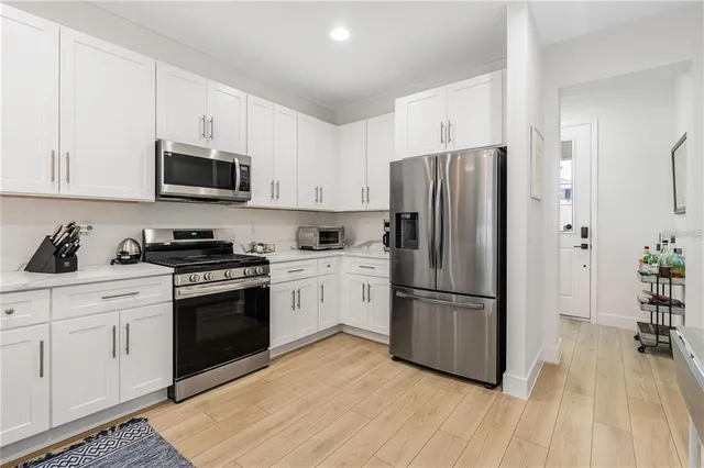 a kitchen with cabinets stainless steel appliances and wooden floor