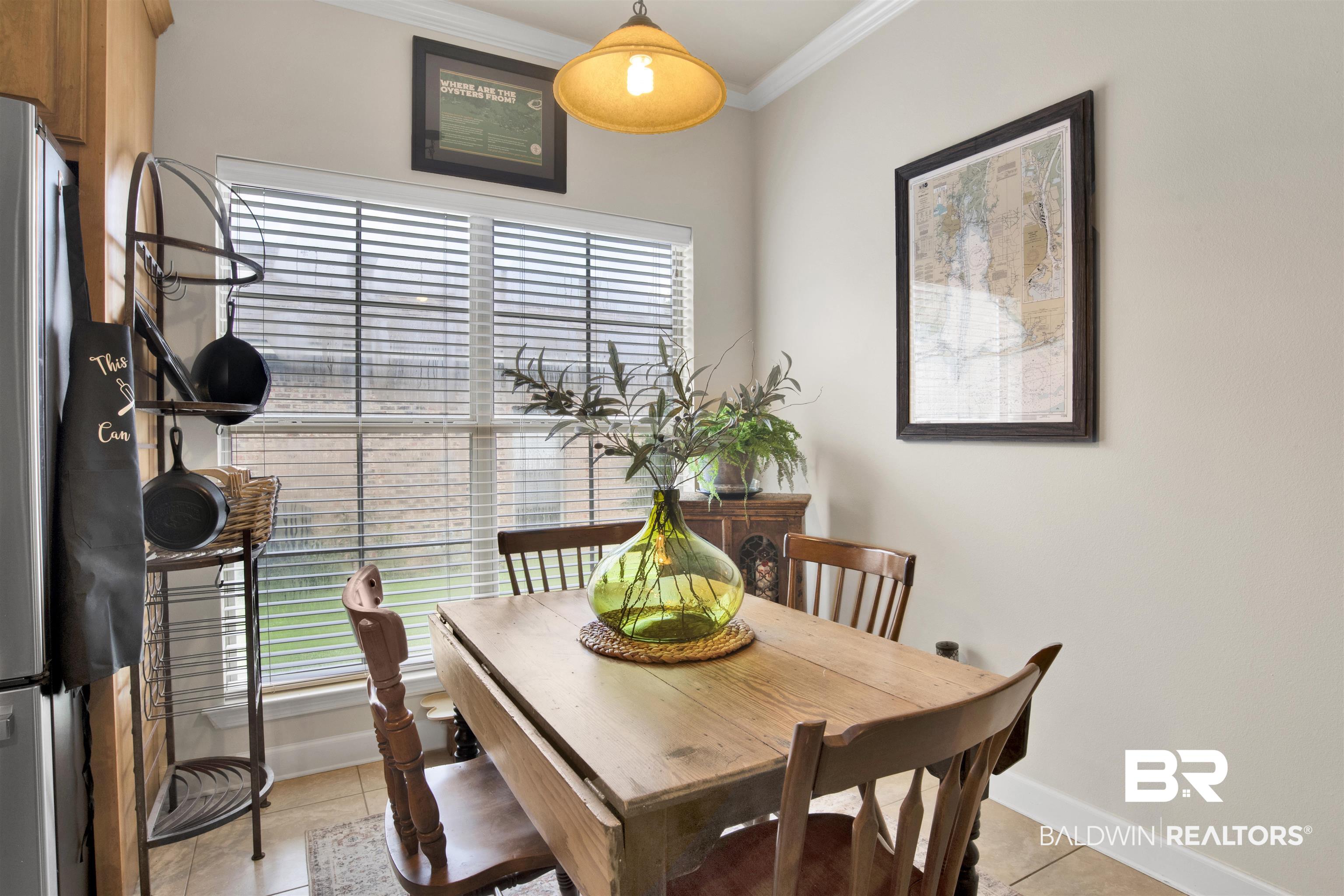 10368 Gayfer Rd Extension Fairhope, AL 36532 - Photo 17 of 43 Dining area featuring a drop-leaf wood table, crown molding, and tiled flooring