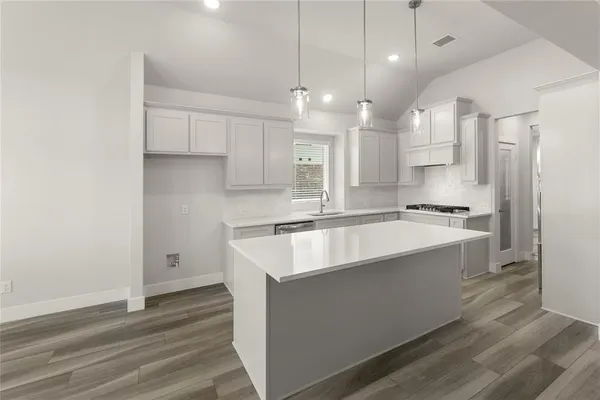 a large kitchen with kitchen island a stove a sink dishwasher and a refrigerator with wooden floor