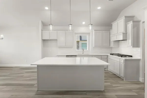 a large white kitchen with kitchen island a sink stainless steel appliances and cabinets
