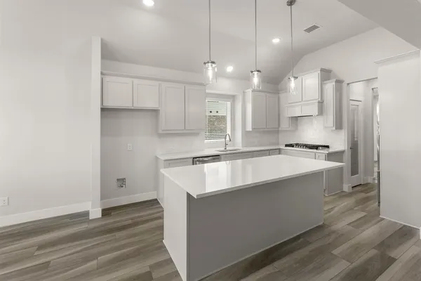 a large kitchen with kitchen island a stove a sink dishwasher and a refrigerator with wooden floor