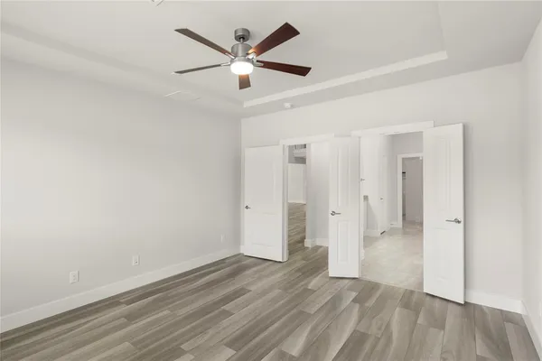 an empty room with wooden floor and a ceiling fan