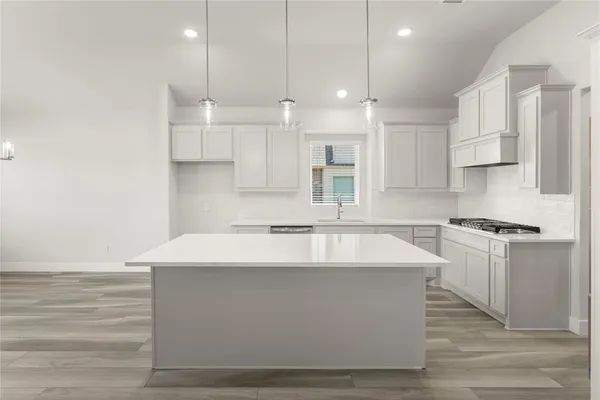 a large white kitchen with kitchen island a sink stainless steel appliances and cabinets