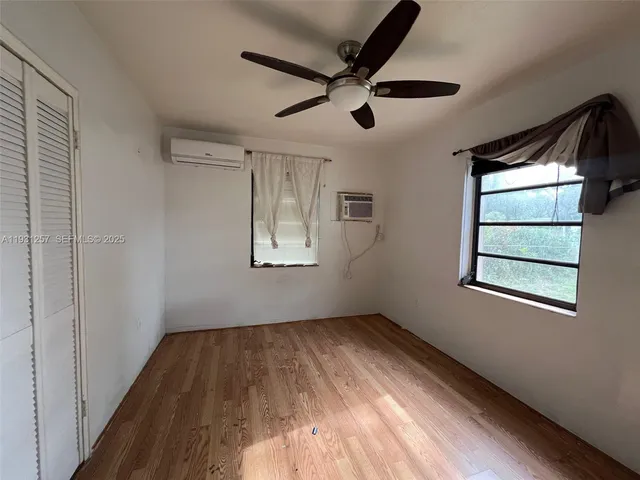 a view of empty room with wooden floor and fan