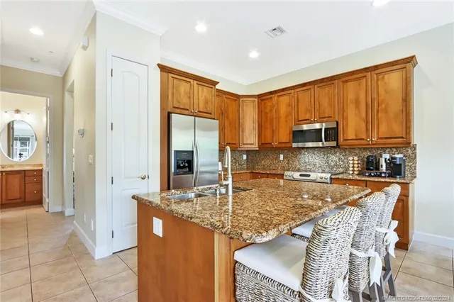 a kitchen with stainless steel appliances granite countertop a refrigerator a stove top oven and a sink with granite countertops