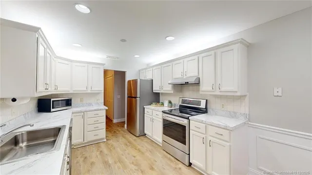 a kitchen with stainless steel appliances white cabinets and a refrigerator