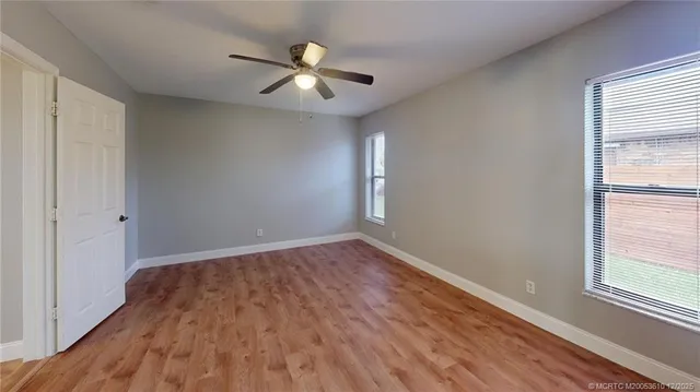 a view of an empty room with window and wooden floor