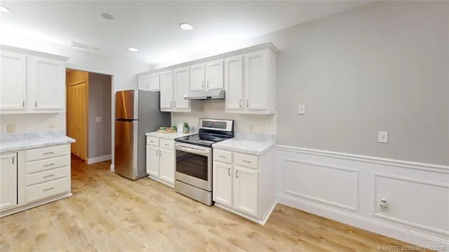 a kitchen with white cabinets and stainless steel appliances