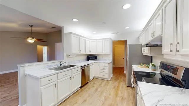 a kitchen that has a lot of cabinets in it and wooden floors