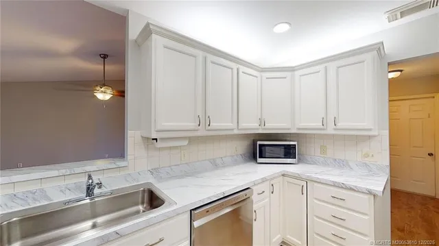 a kitchen with granite countertop a sink cabinets and stainless steel appliances