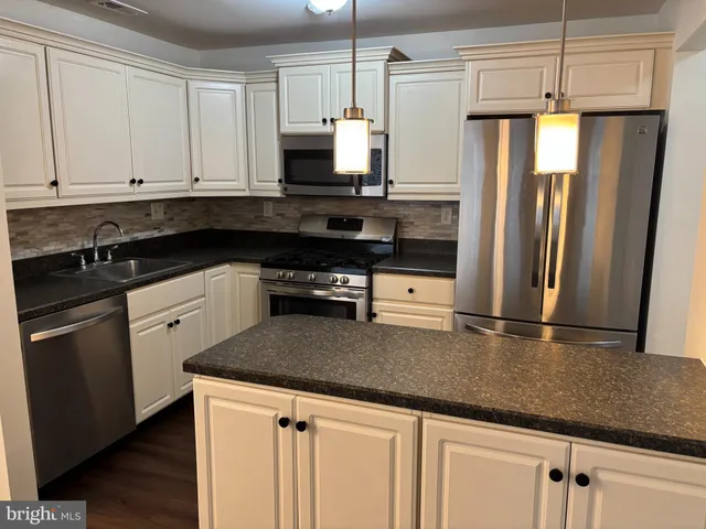 a kitchen with granite countertop white cabinets and stainless steel appliances