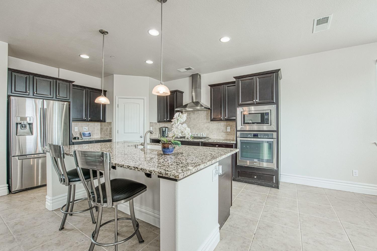 3036 Portals Avenue Clovis, CA 93619 - Photo 21 of 53 a kitchen with stainless steel appliances kitchen island granite countertop a sink refrigerator and cabinets