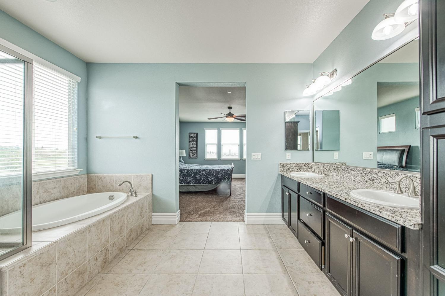 3036 Portals Avenue Clovis, CA 93619 - Photo 40 of 53 a spacious bathroom with a granite countertop tub sink and mirror