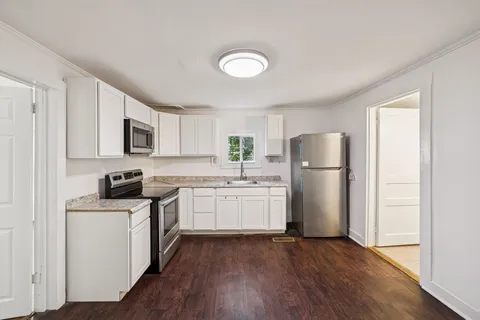 a kitchen with a refrigerator a stove top oven a sink and dishwasher with wooden floor