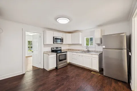 a kitchen with a refrigerator stove and wooden floor