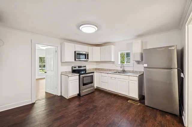 a kitchen with a refrigerator stove and wooden floor