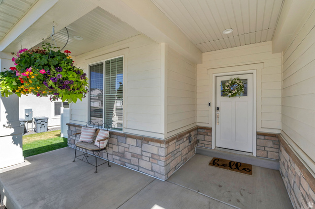2664 West Maple Street Mapleton, UT 84664 - Photo 38 of 49 Covered front porch featuring a white panel door with decorative glass, cream horizontal siding, and a stone veneer foundation