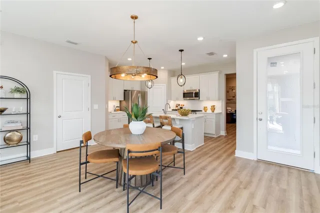 a view of a dining room and livingroom with furniture wooden floor a chandelier