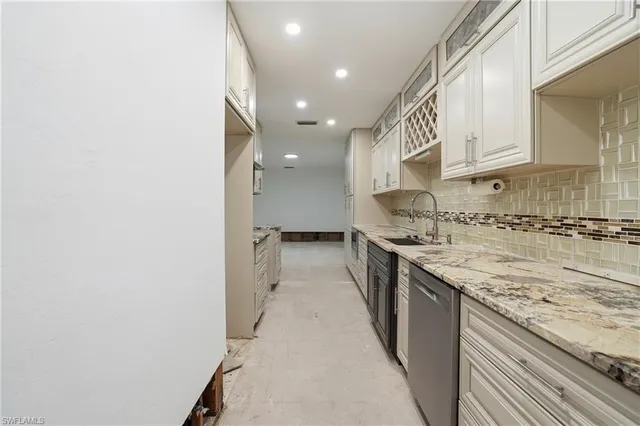 an empty room with granite countertop kitchen island a stove a sink and a refrigerator