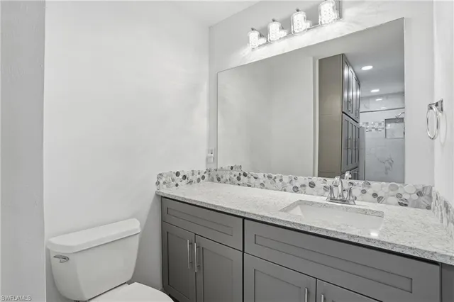 a bathroom with a granite countertop sink mirror and toilet