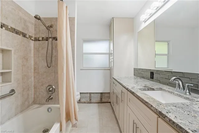a bathroom with a granite countertop sink mirror bathtub and shower