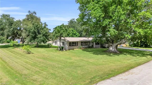 a view of a house with a big yard and large trees