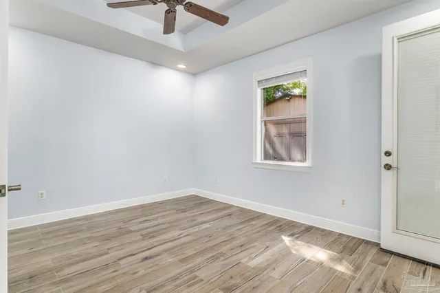 an empty room with wooden floor fan and windows