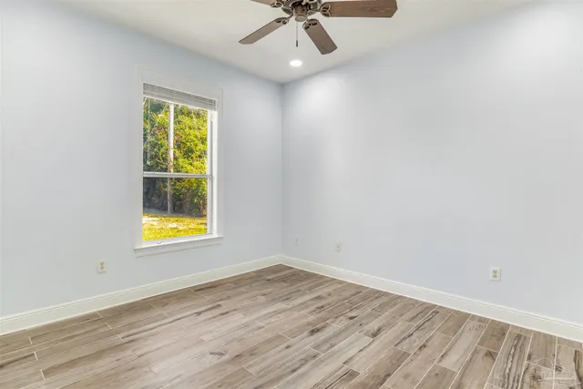 an empty room with wooden floor a ceiling fan and staircase