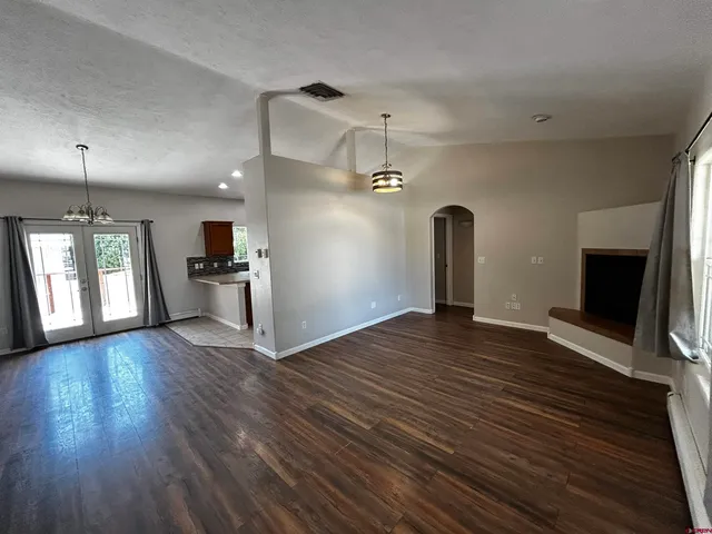 an empty room with wooden floor fireplace and windows