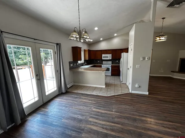 a view of a big room with wooden floor and a kitchen