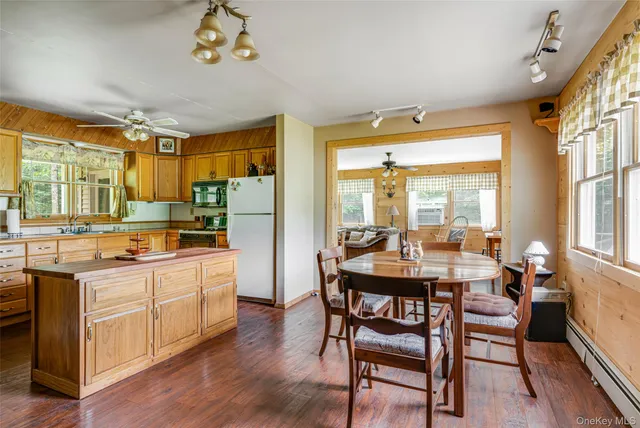 a kitchen with a refrigerator a stove a sink dishwasher a dining table and chairs with wooden floor