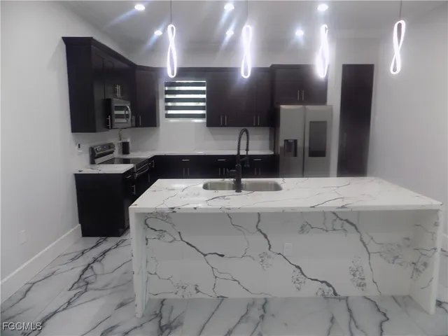 a kitchen with stainless steel appliances kitchen island granite countertop a refrigerator and a stove top oven