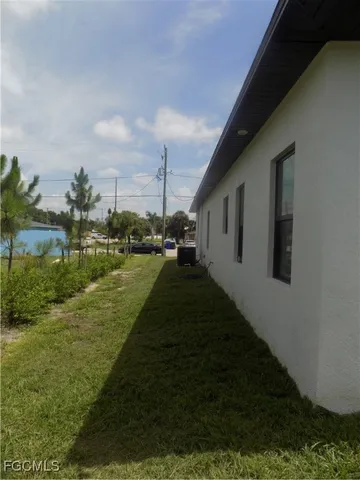 a view of a refrigerator in kitchen and an empty room with wooden floor