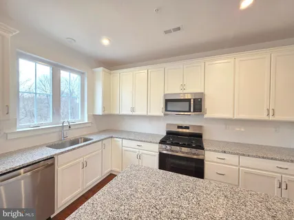 a kitchen with stainless steel appliances granite countertop a stove a sink and a white cabinets