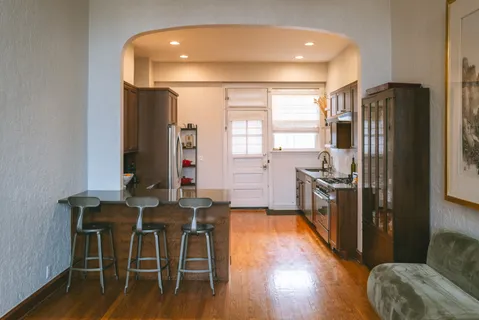 a kitchen with stainless steel appliances a dining table chairs stove refrigerator and cabinets