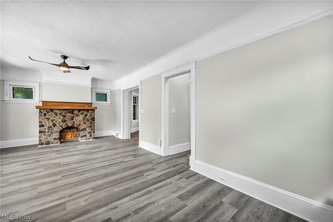 1659 Lee Road Cleveland, OH 44118 - Photo 7 of 46 Stone-clad fireplace with a wood mantle, wood-finish flooring, and a ceiling fan