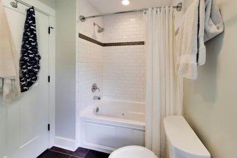 a bathroom with a bathtub shower and toilet