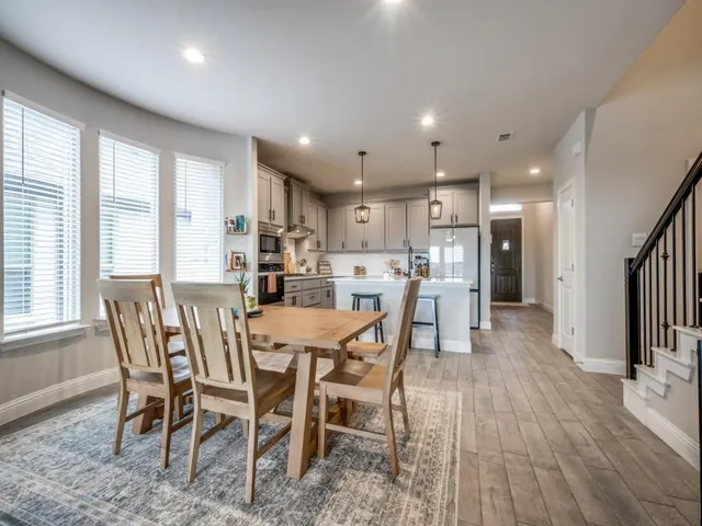 a view of a dining room and livingroom with furniture wooden floor a rug a painting and a chandelier