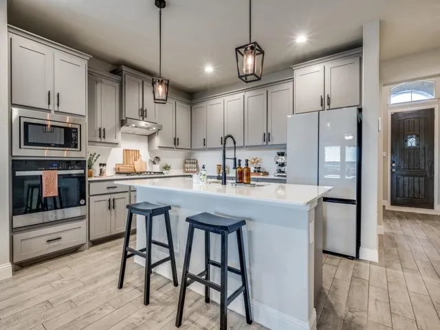 a kitchen with stainless steel appliances granite countertop a stove a sink a refrigerator and a microwave