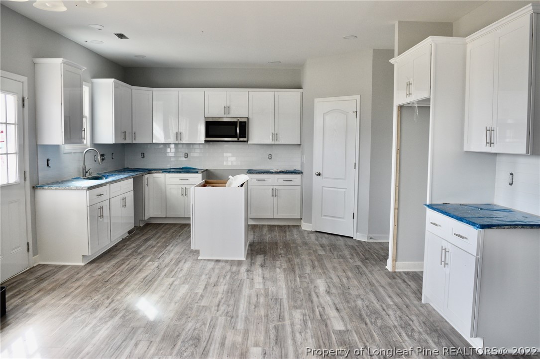 263 McMillan Siding Road Parkton, NC 28371 - Photo 4 of 15 a kitchen with stainless steel appliances white cabinets sink and wooden floor