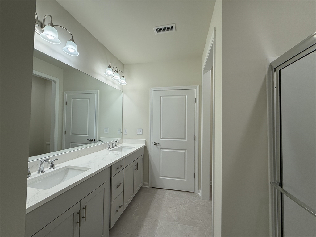 4 Winslow Lane, Unit 1411 North Grafton, MA 01536 - Photo 34 of 36 a spacious bathroom with a double vanity sink and mirror