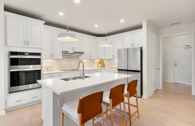 a kitchen with stainless steel appliances granite countertop a table chairs sink and cabinets